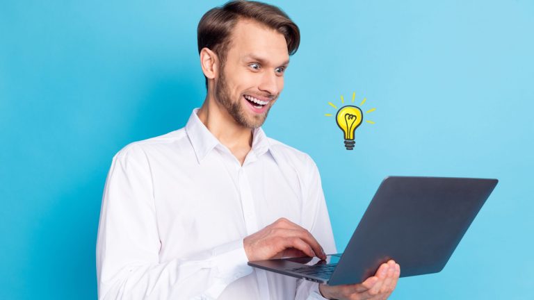 גבר צעיר מביט בהתלהבות במסך הלפטופ